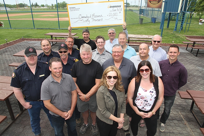 Enbridge contributed $60,000 to projects in Moosomin in a cheque presentation at the Tim Hortons Outdoor Eventplex on Wednesday, June 13 -- $35,000 will go toward developing an outdoor event-plex and a hot tub project, while $25,000 will be used by the Moosomin Fire Department toward purchase of a new aerial platform truck. Pictured are (front row, from left) Ryan Kitchen and Joanne Bradbury, Enbridge; Catherine Mannle (assistant recreation director). Second and third rows (from left):  Peter Nabholz, Chief Rob Hanson, Mike Cooper and Trevor Green (Moosomin Fire Department); Murray Gray (counc